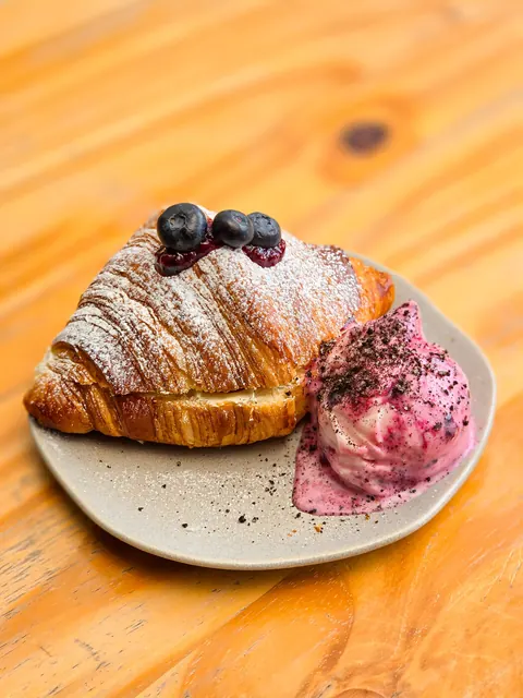 Croissant decorado con frutos rojos junto a una bola de helado