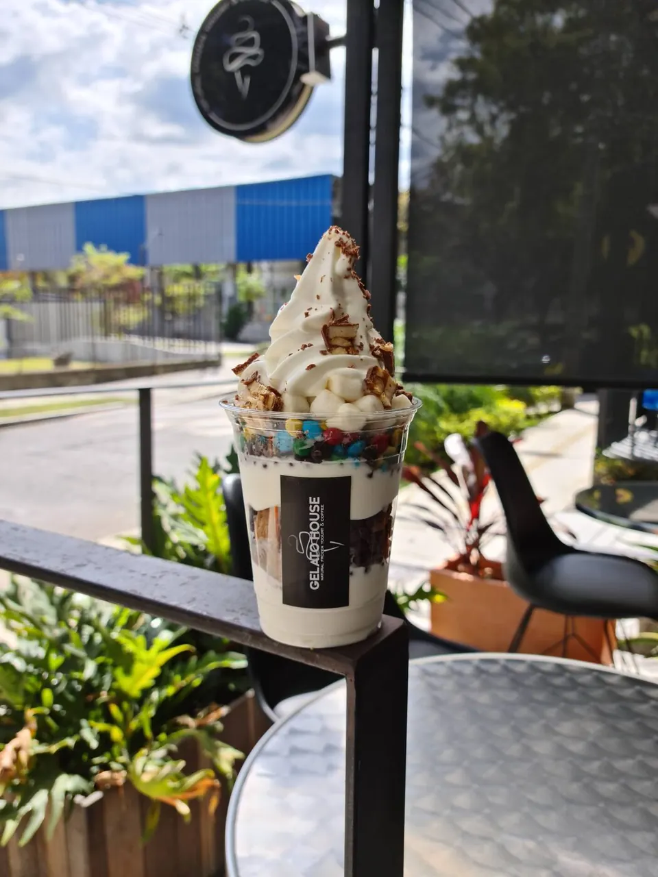 Vaso de helado de yogurt con toppings en la terraza del local